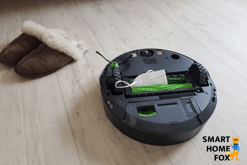 Man sieht den Roomba j7 von unten während eine Atemschutzmaske die beiden Gummibürsten blockiert